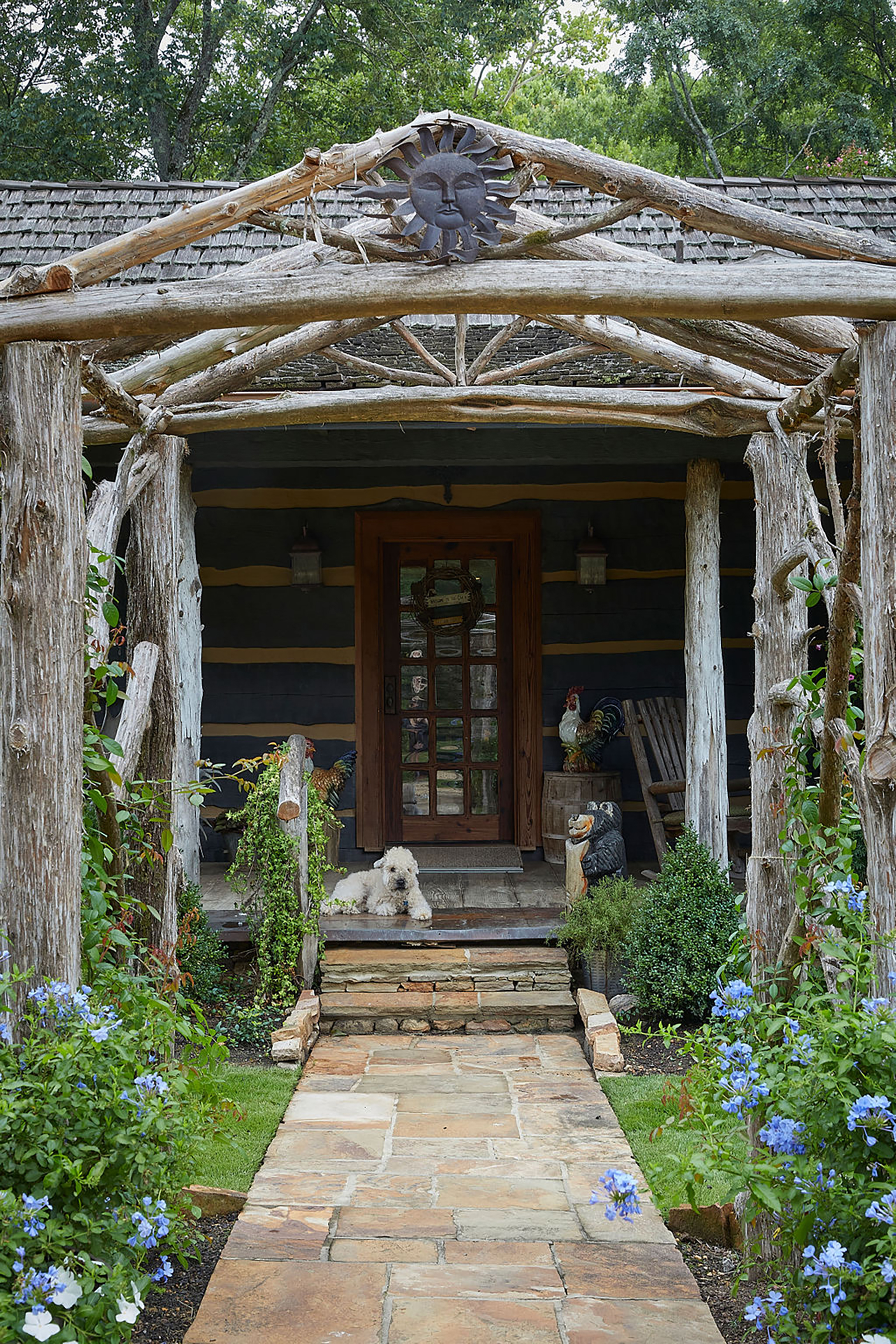 Dog sitting on front porch under a cedar arbor