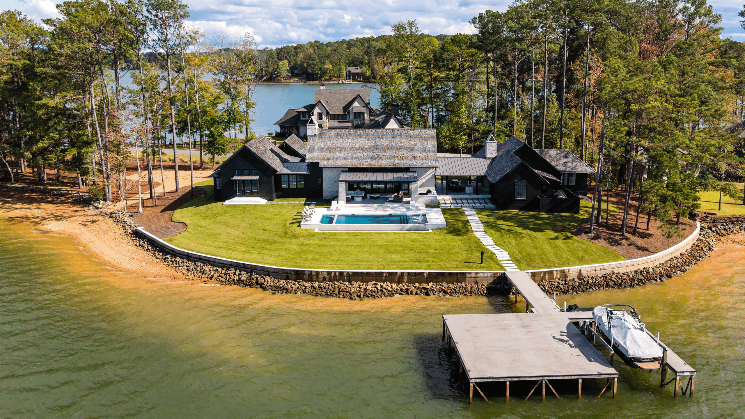 Elevated front view of a modern one-story home at Lake Martin featuring white stone and black vertical siding.