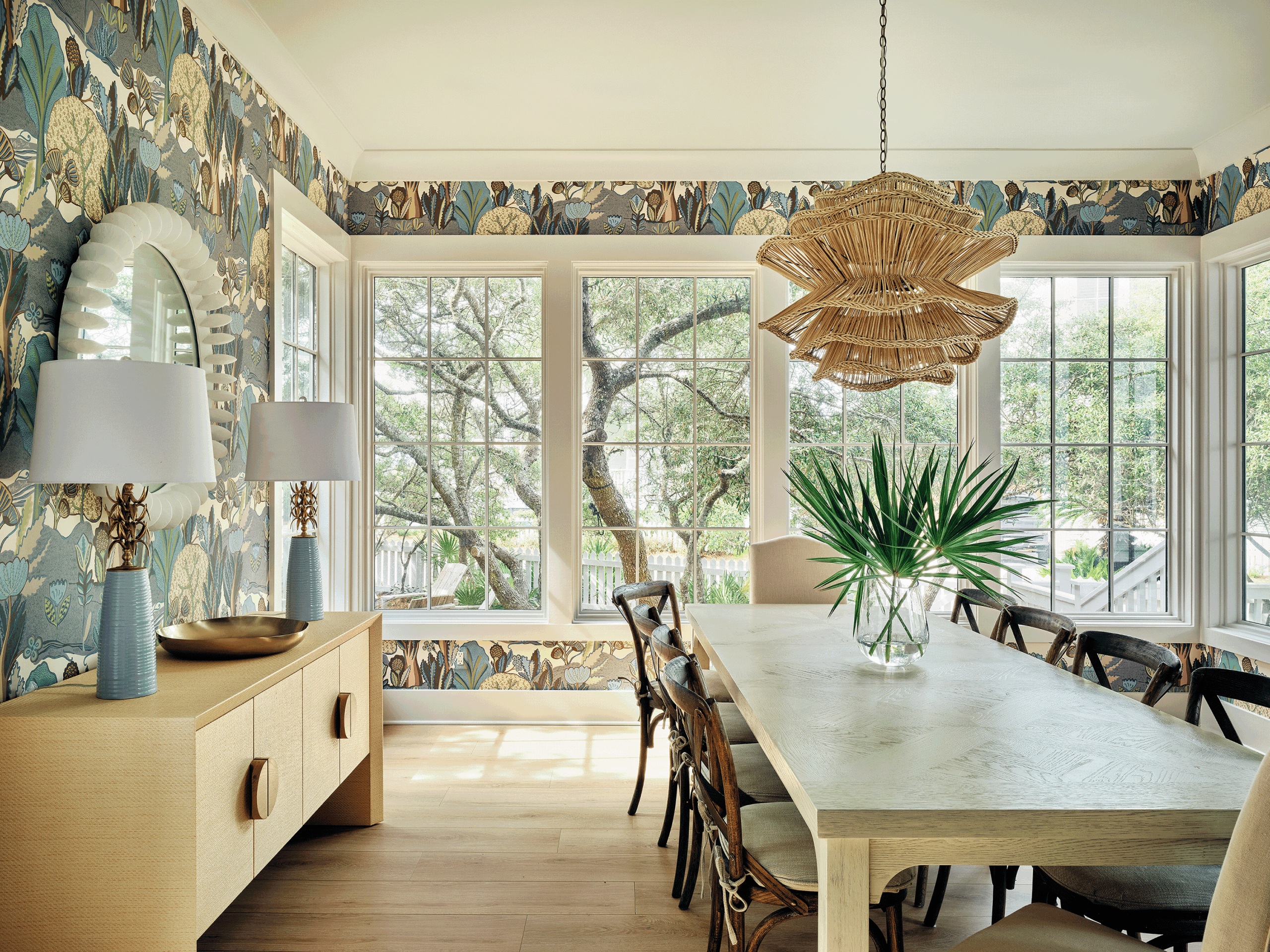 Sun-drenched dining room with floor-to-ceiling windows and a long wooden table for hosting large groups when sharing a vacation home.