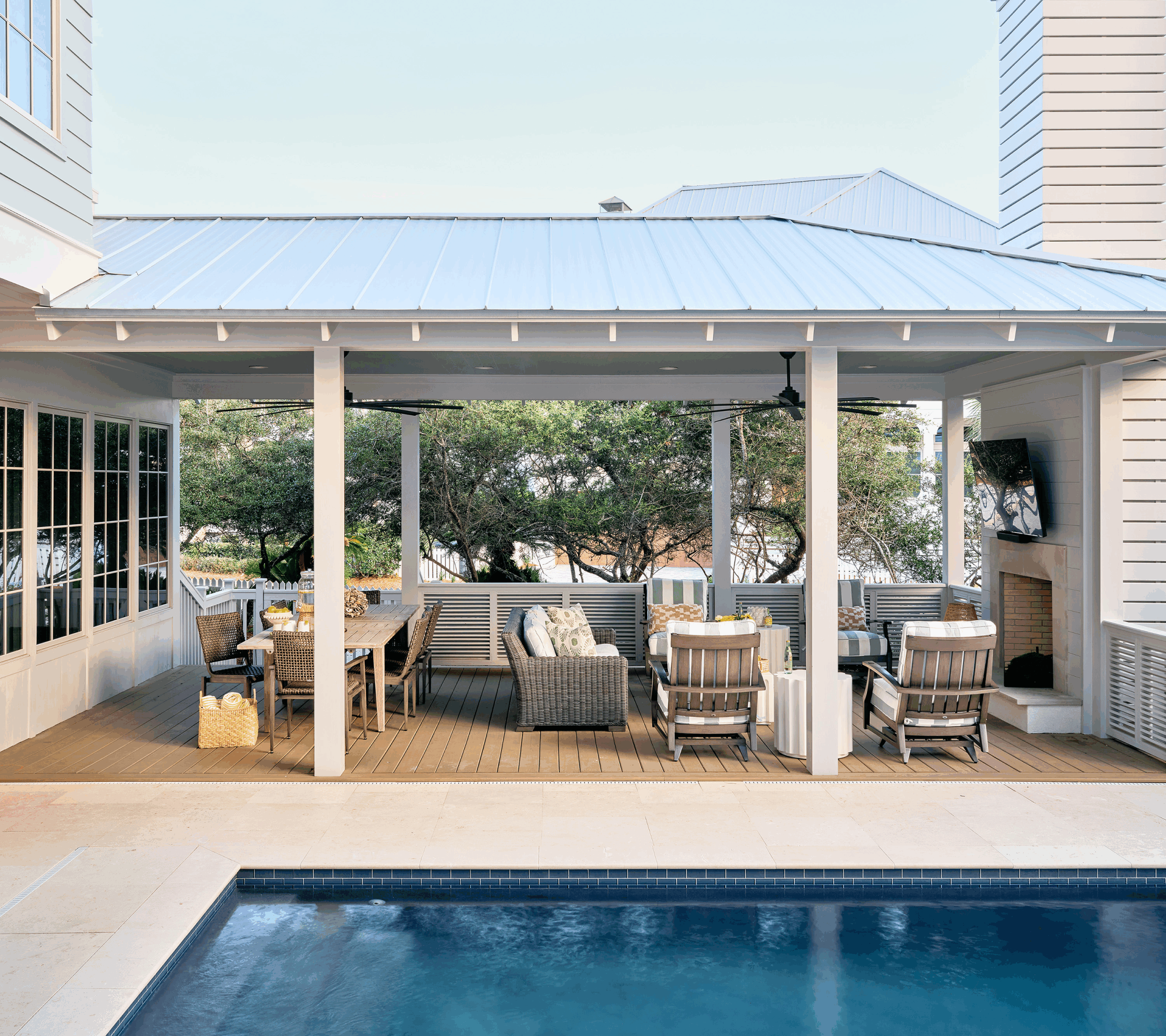 Large screened-in porch with a modern fireplace and ample seating, designed for comfortable group living and sharing a vacation home.