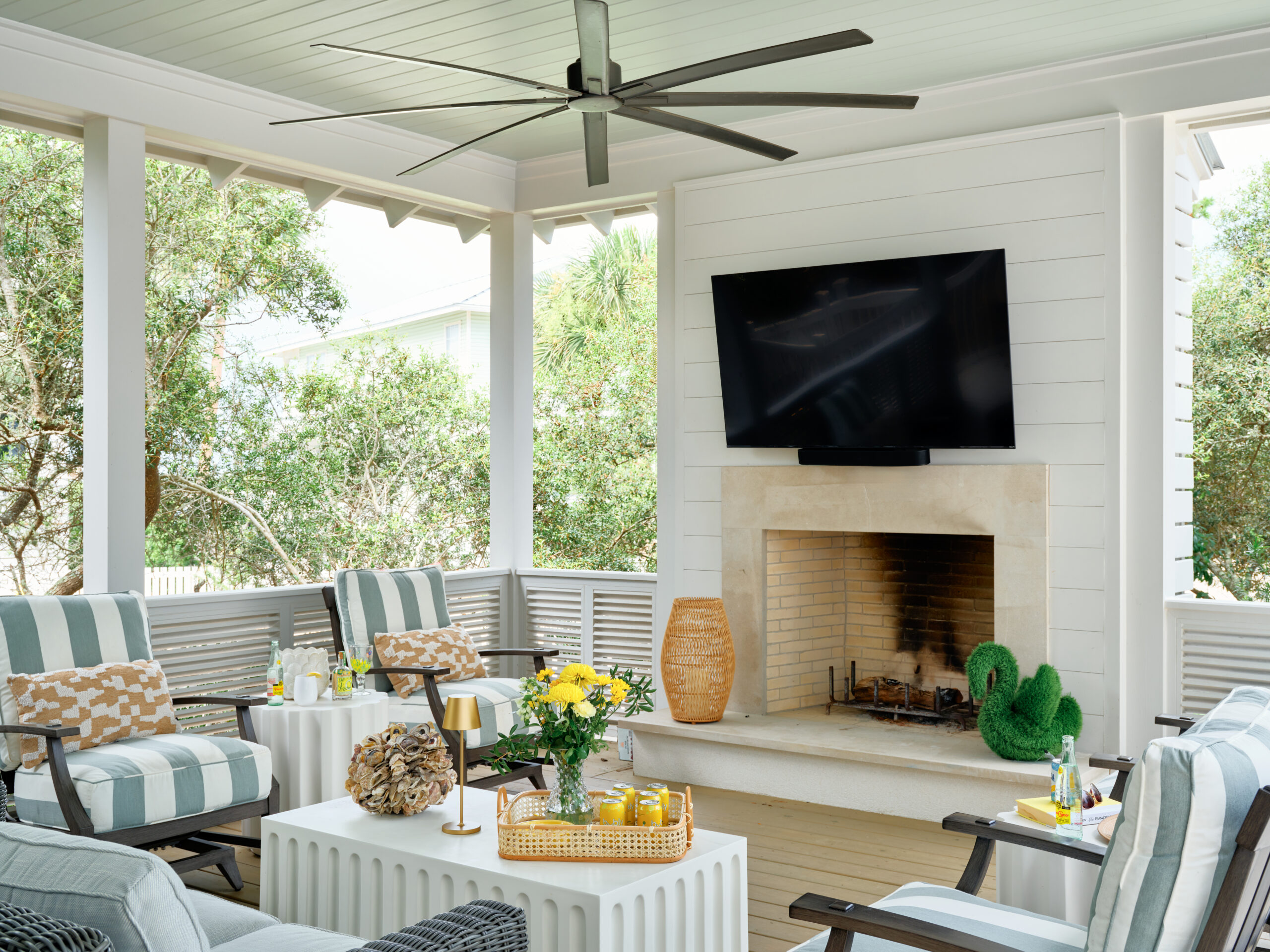 Expansive porch of a beach house with a brick fireplace and comfortable lounge seating for outdoor living.