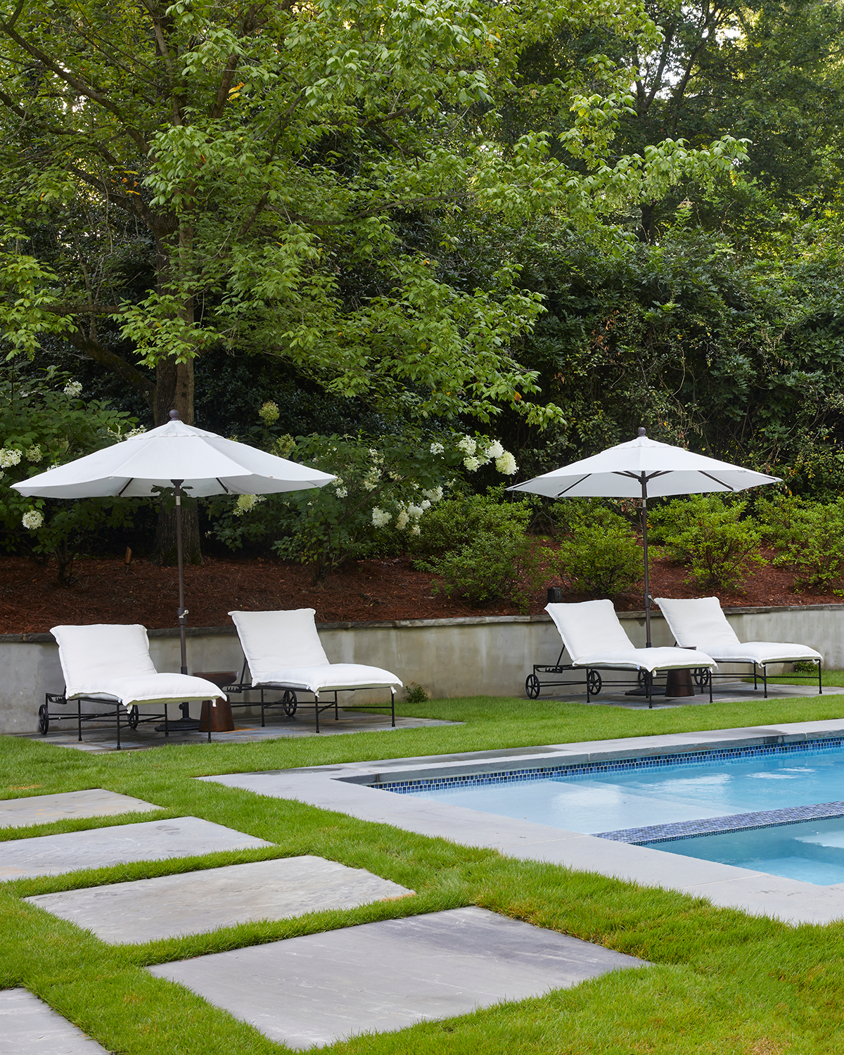 Hamptons-inspired backyard retreat featuring a rectangular pool, white sun loungers, and professional hardscaping.