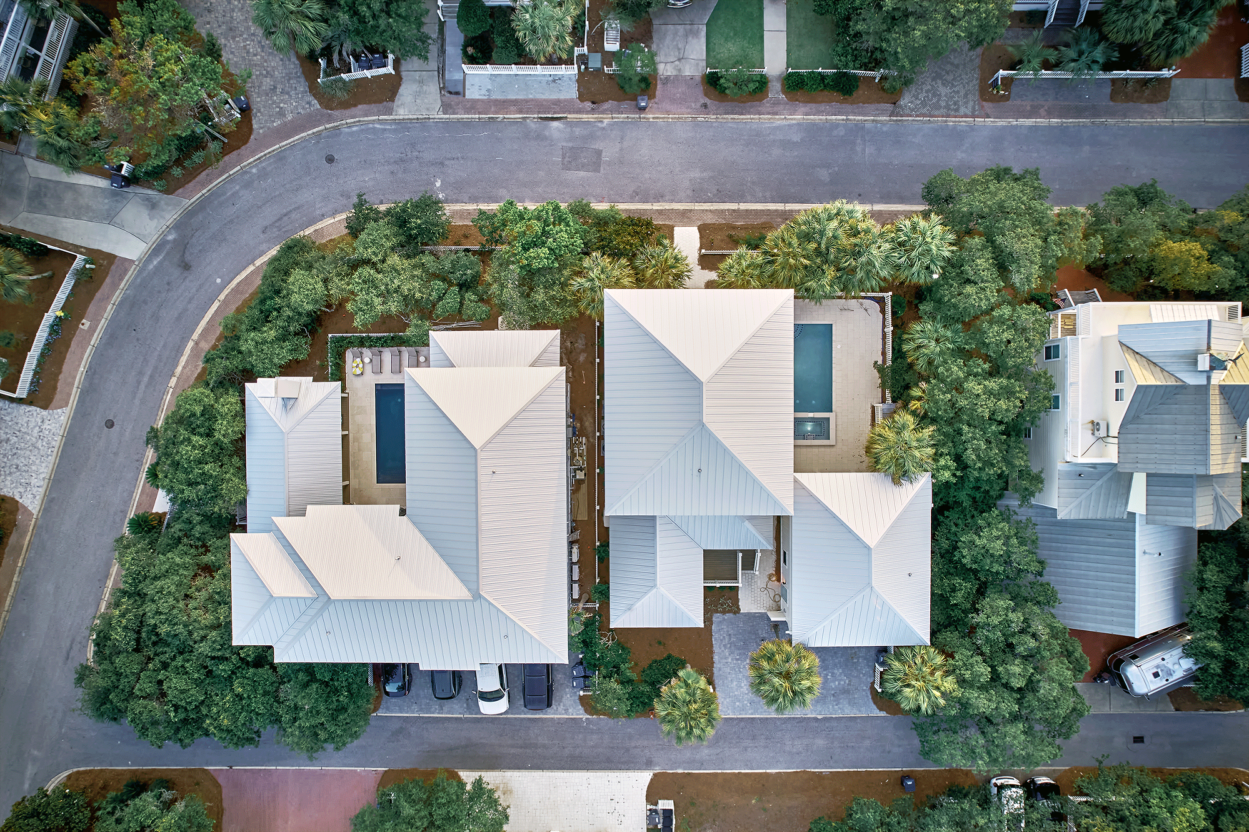 Aerial view of a U-shaped beach house lot showing the pool area and ample off-street parking for multiple vehicles.