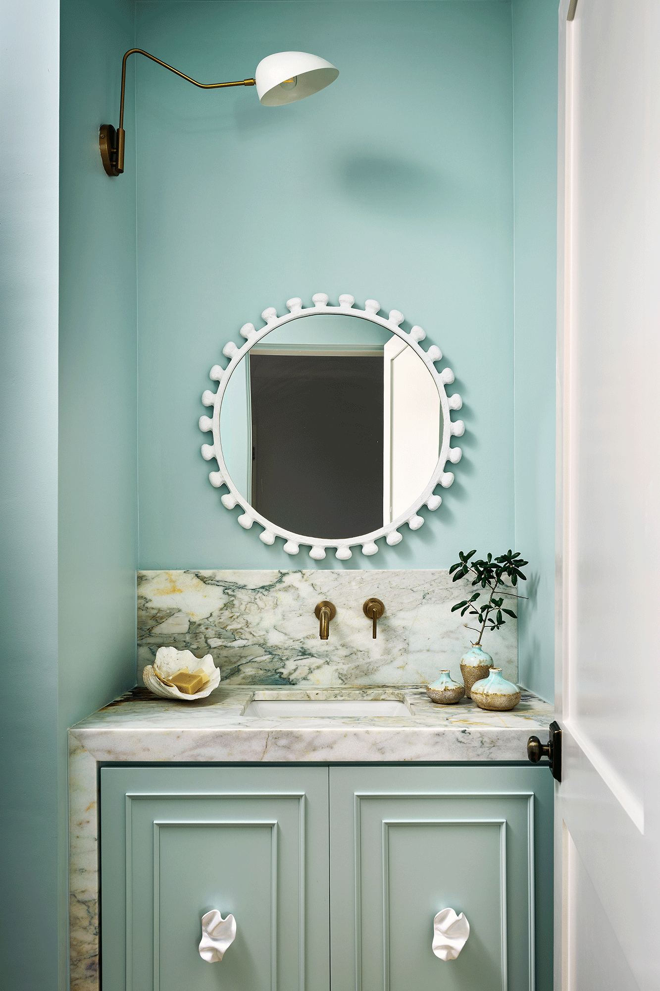 Compact guest bathroom in a beach house with a white pedestal sink and clean, minimalist design for visitor privacy.