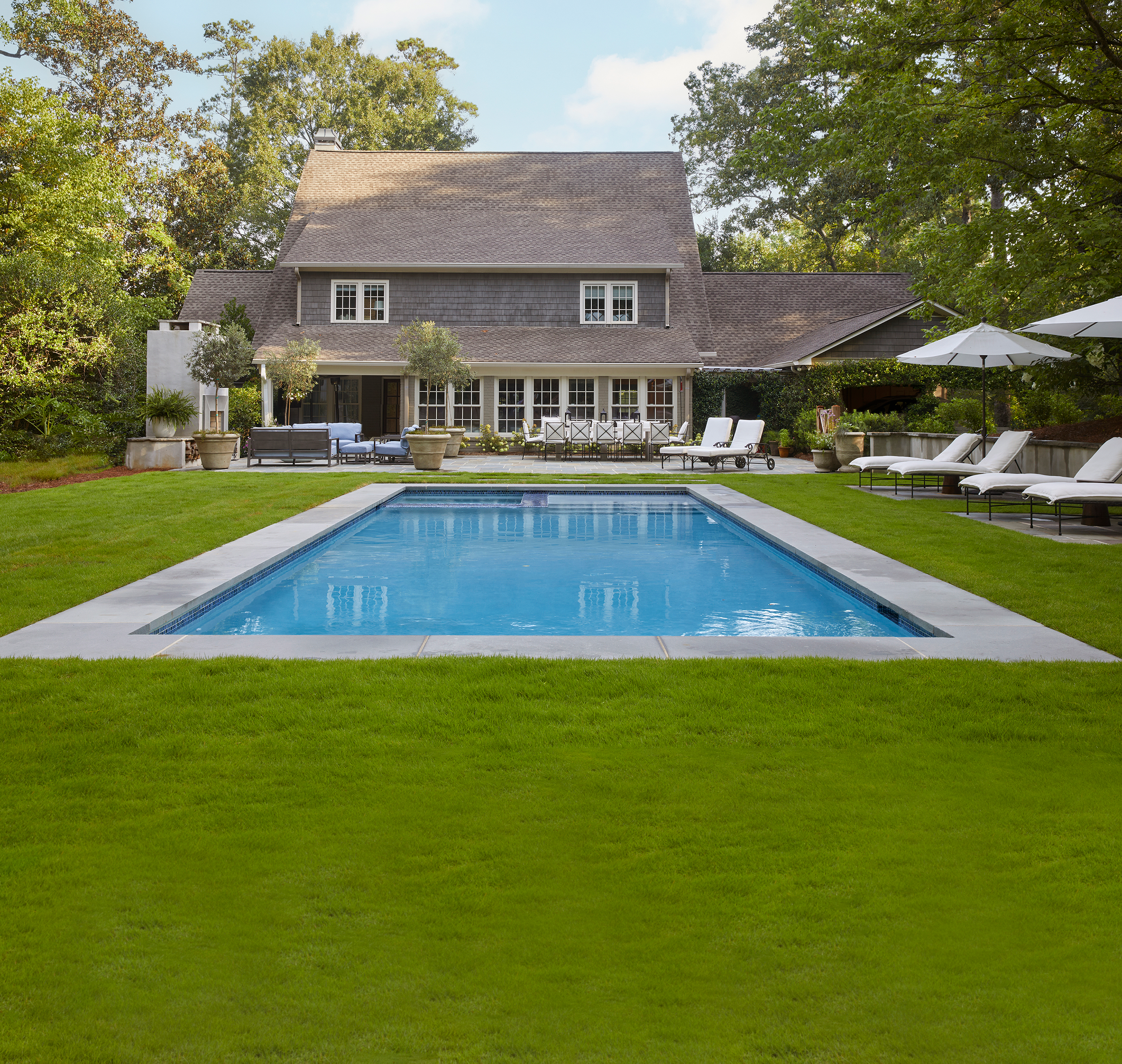 Large Hamptons style rectangular pool and expansive level lawn in a luxury backyard designed by Millhouse Howell Landscape Company.