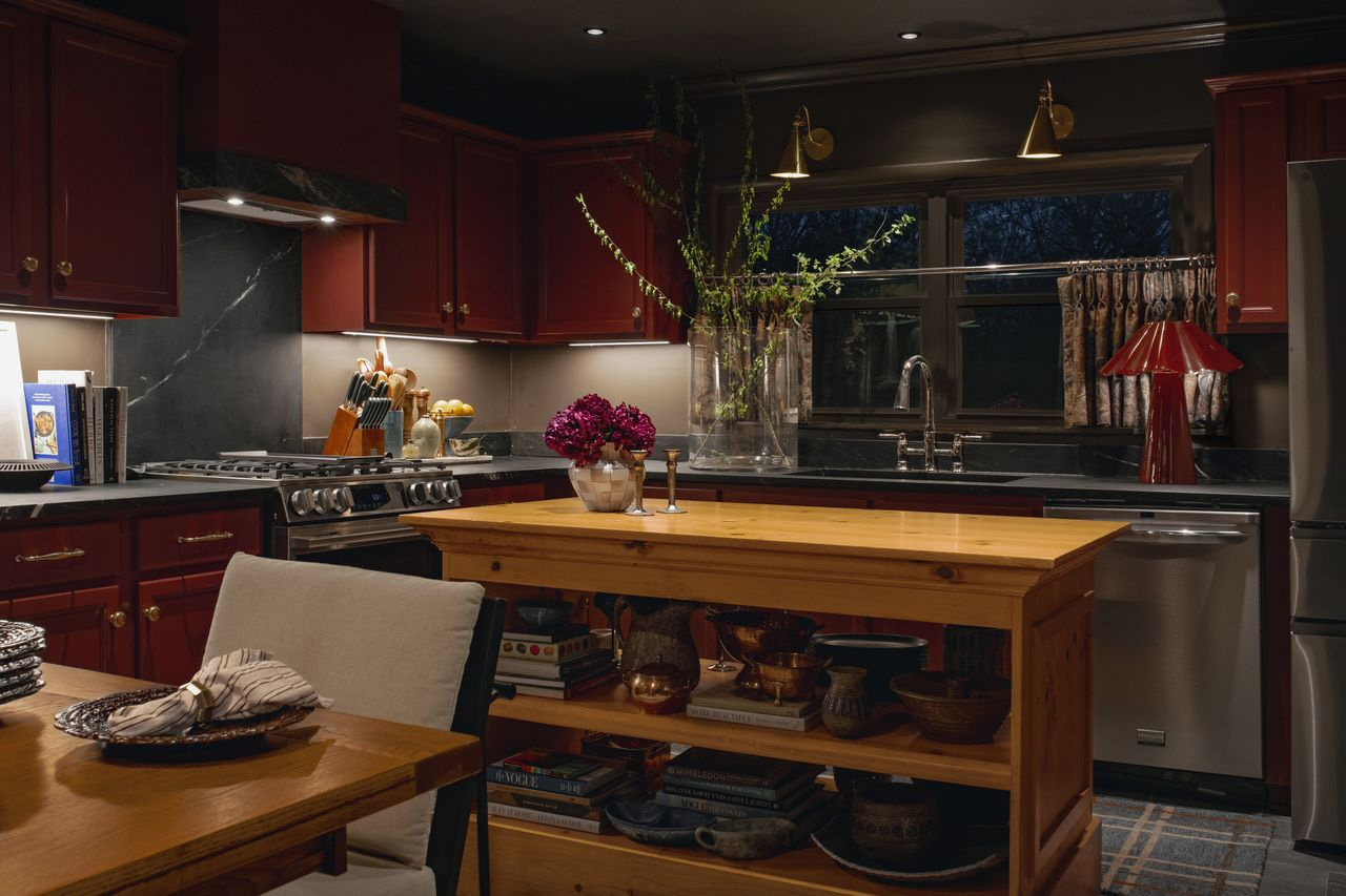 Moody cottage kitchen with oxblood-red cabinets and honed soapstone countertops, an alternative take on the white kitchen trend