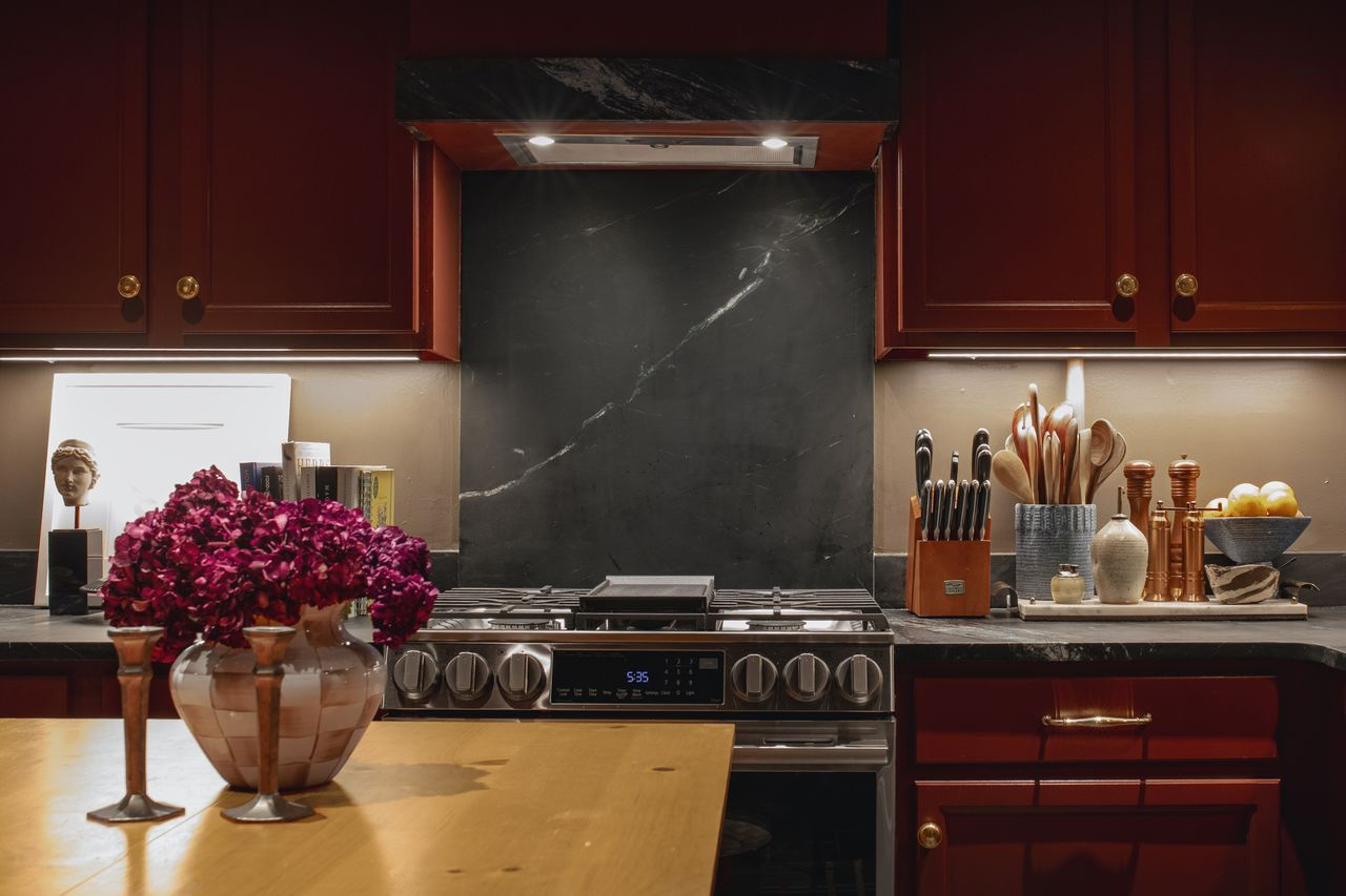 Pine kitchen island and slate tile flooring in a moody cottage-style kitchen designed by Tombrello Collective