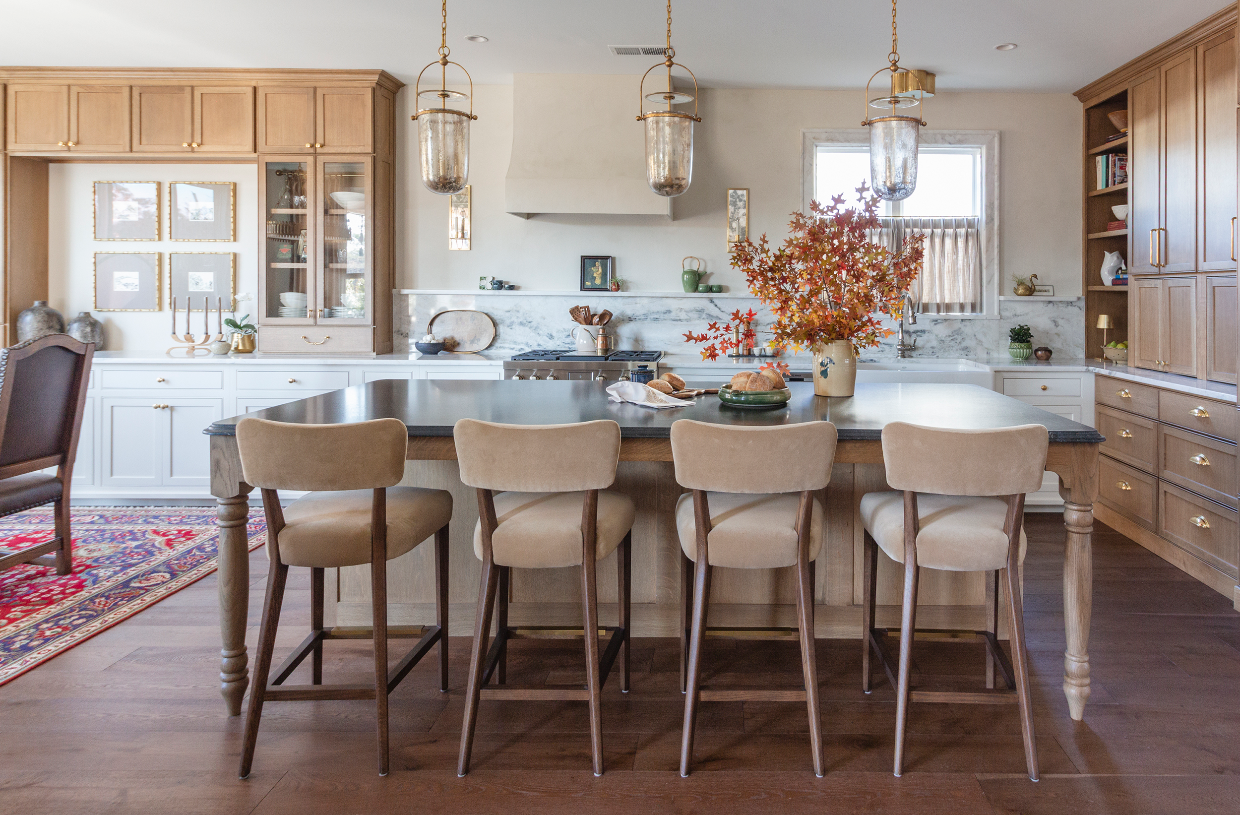 Modern white kitchen featuring warm oak island and brass hardware