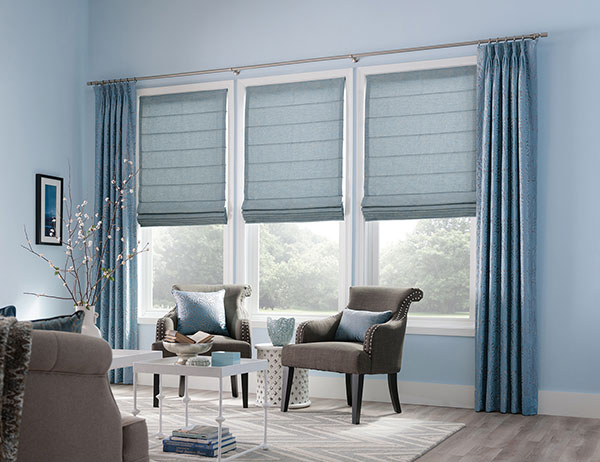 Custom blue Roman shades and coordinating drapery in a bright living room