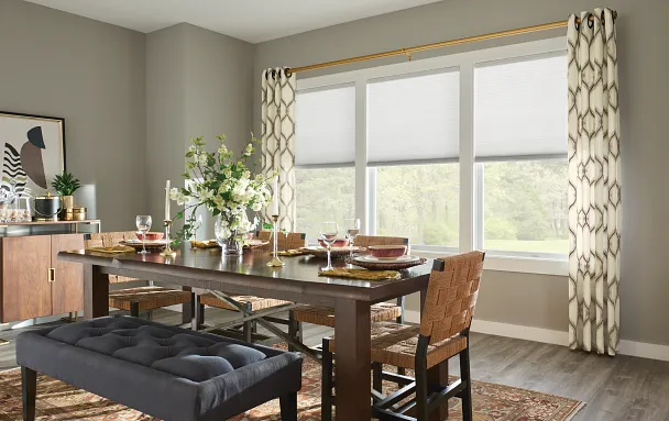 Layered window treatments combining shades and drapery in a dining space