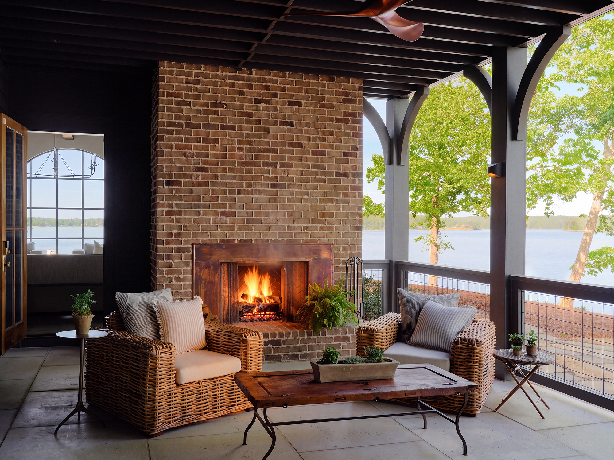 Screened porch with brick fireplace overlooking Lake Martin, dark exterior siding visible beyond