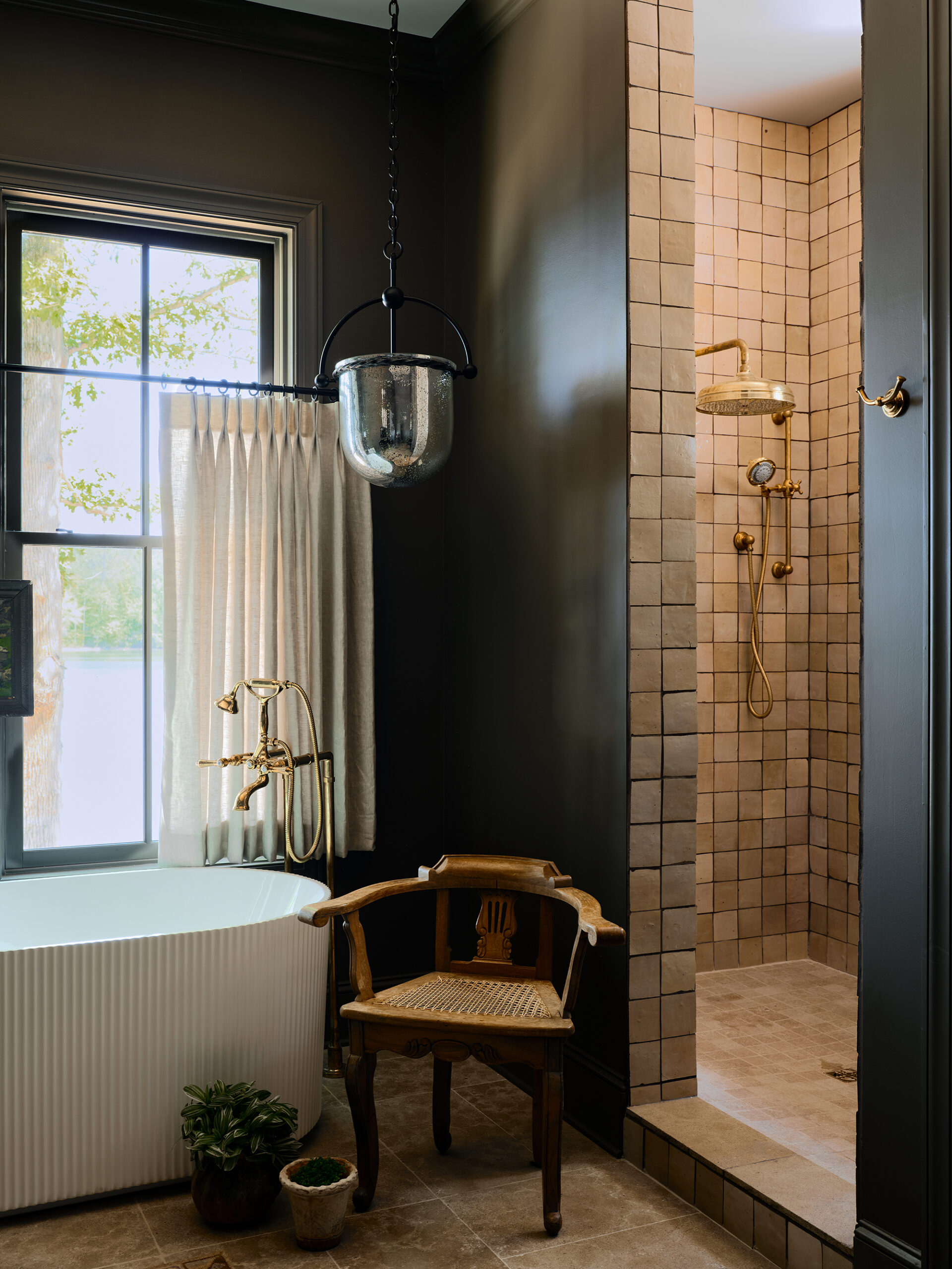 Freestanding tub and brass shower fixtures in a Lake Martin house bathroom designed to age naturally