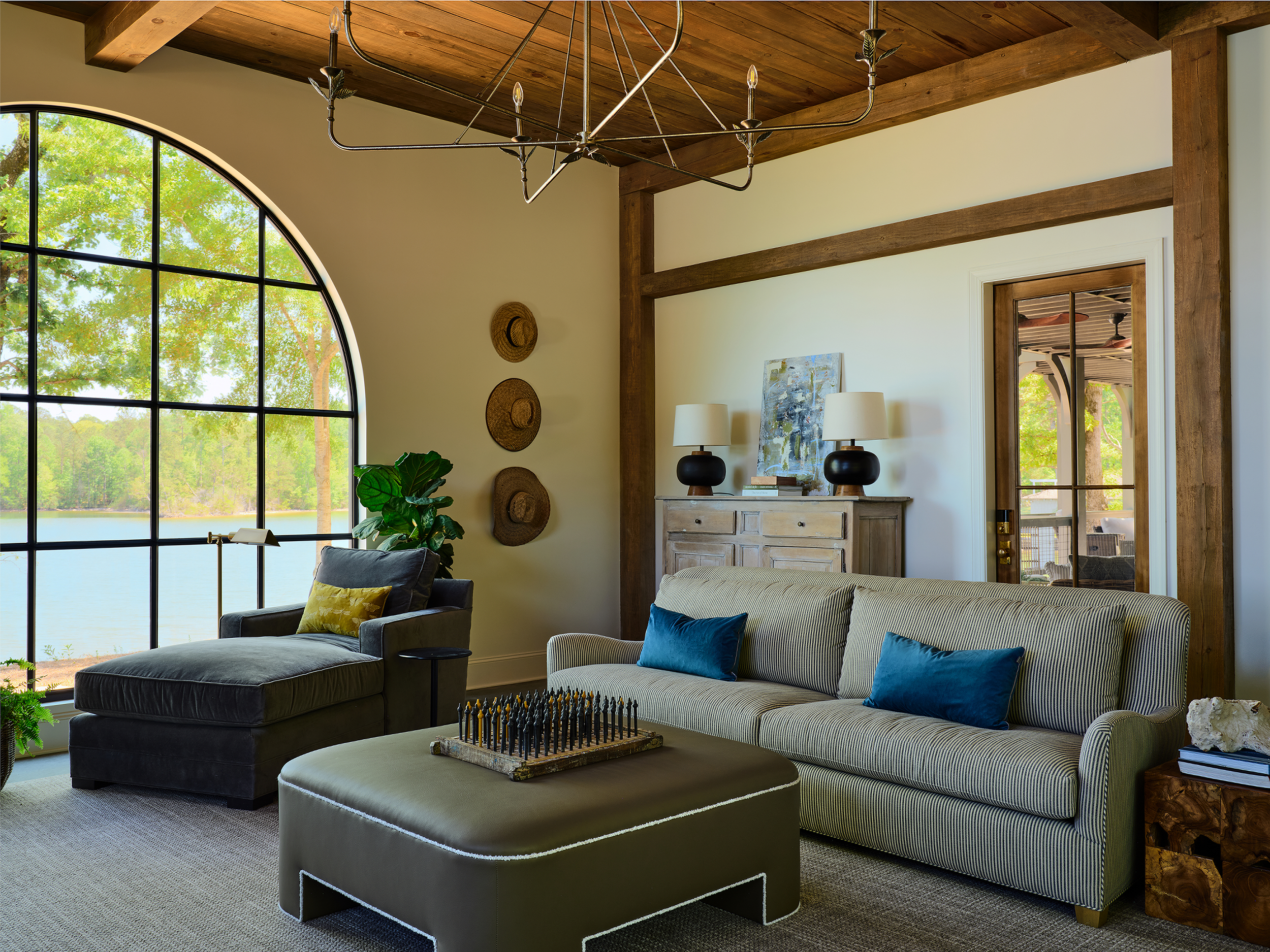 Living room with striped sofa and arched lake-view window adjoining the kitchen