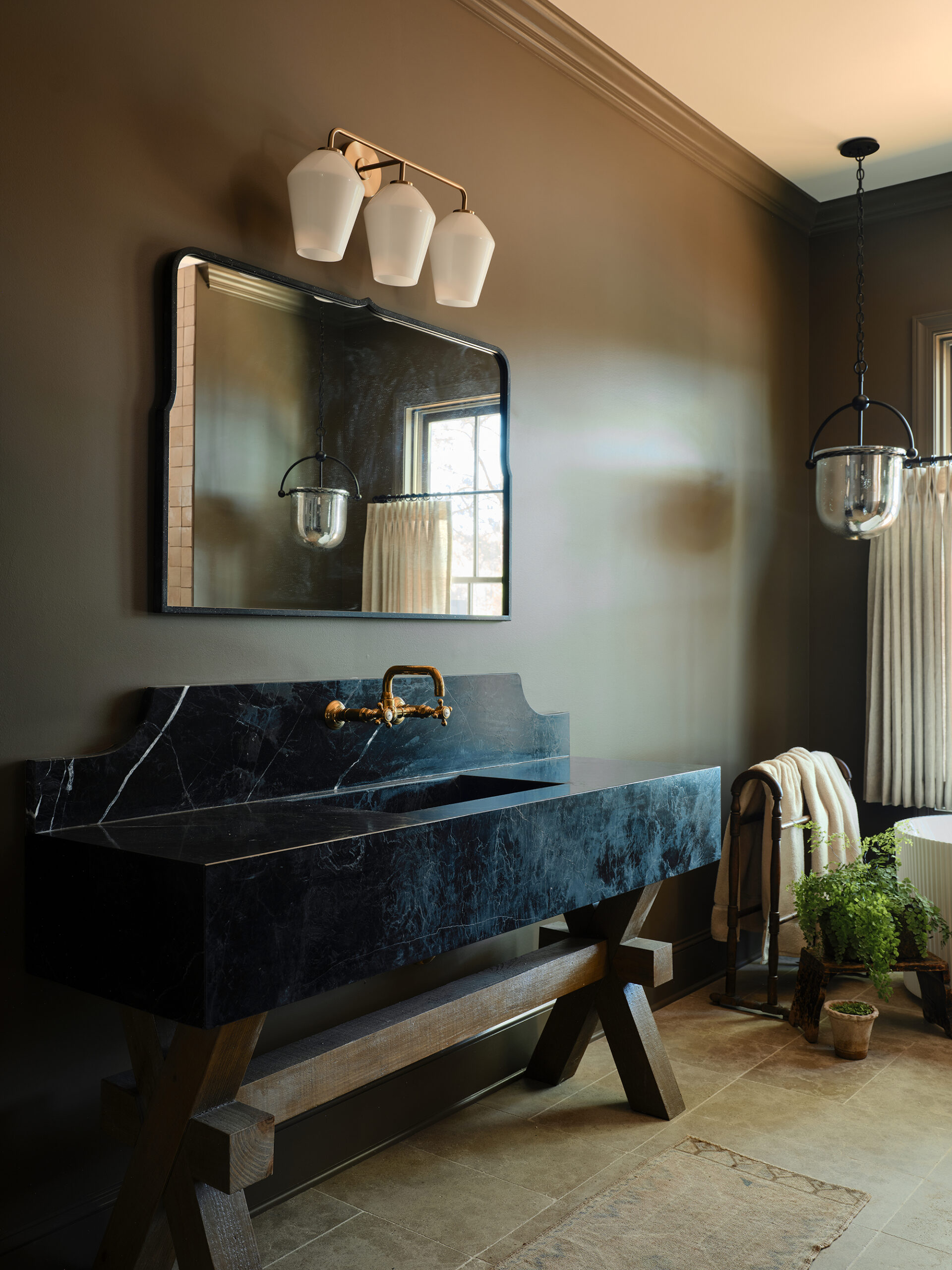 Black marble vanity with unlacquered brass fixtures in a primary bathroom at Lake Martin