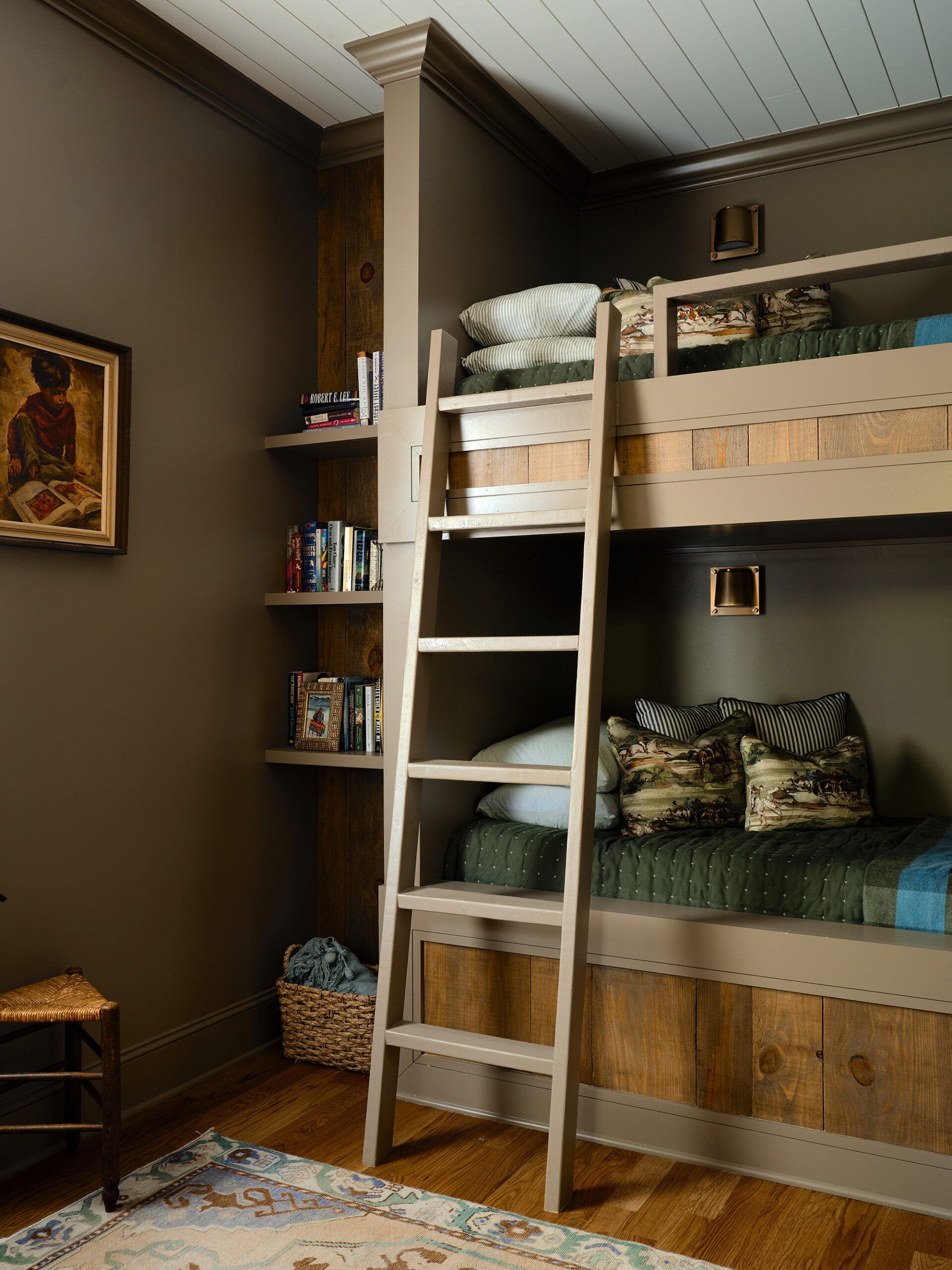 Custom built-in white bunk beds with warm wood ladders in a cozy Lake Martin home bunk room.