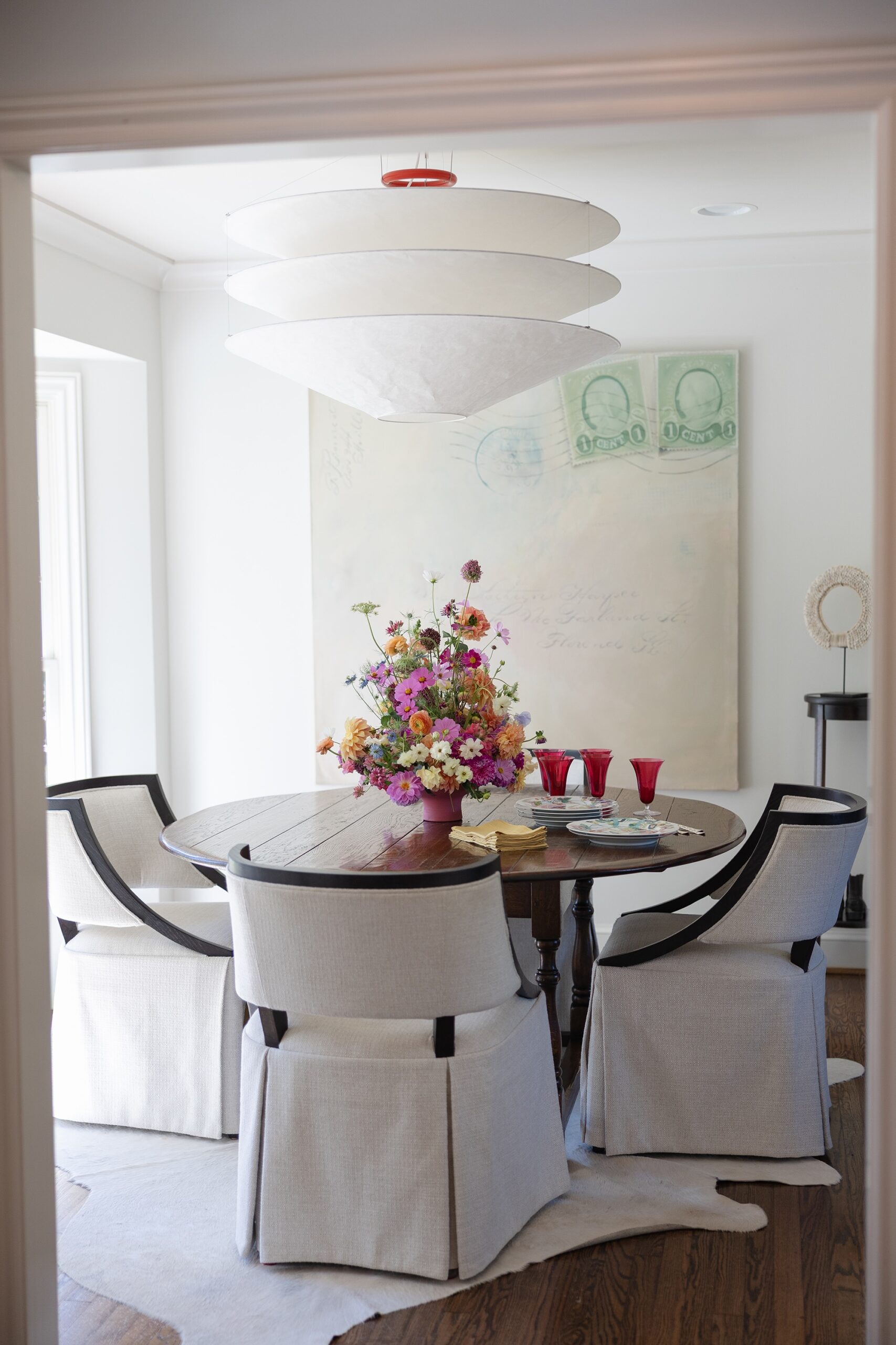 Breakfast room with an antique round table, skirted chairs, a tiered paper lantern, and a flower arrangement in Mountain Brook home