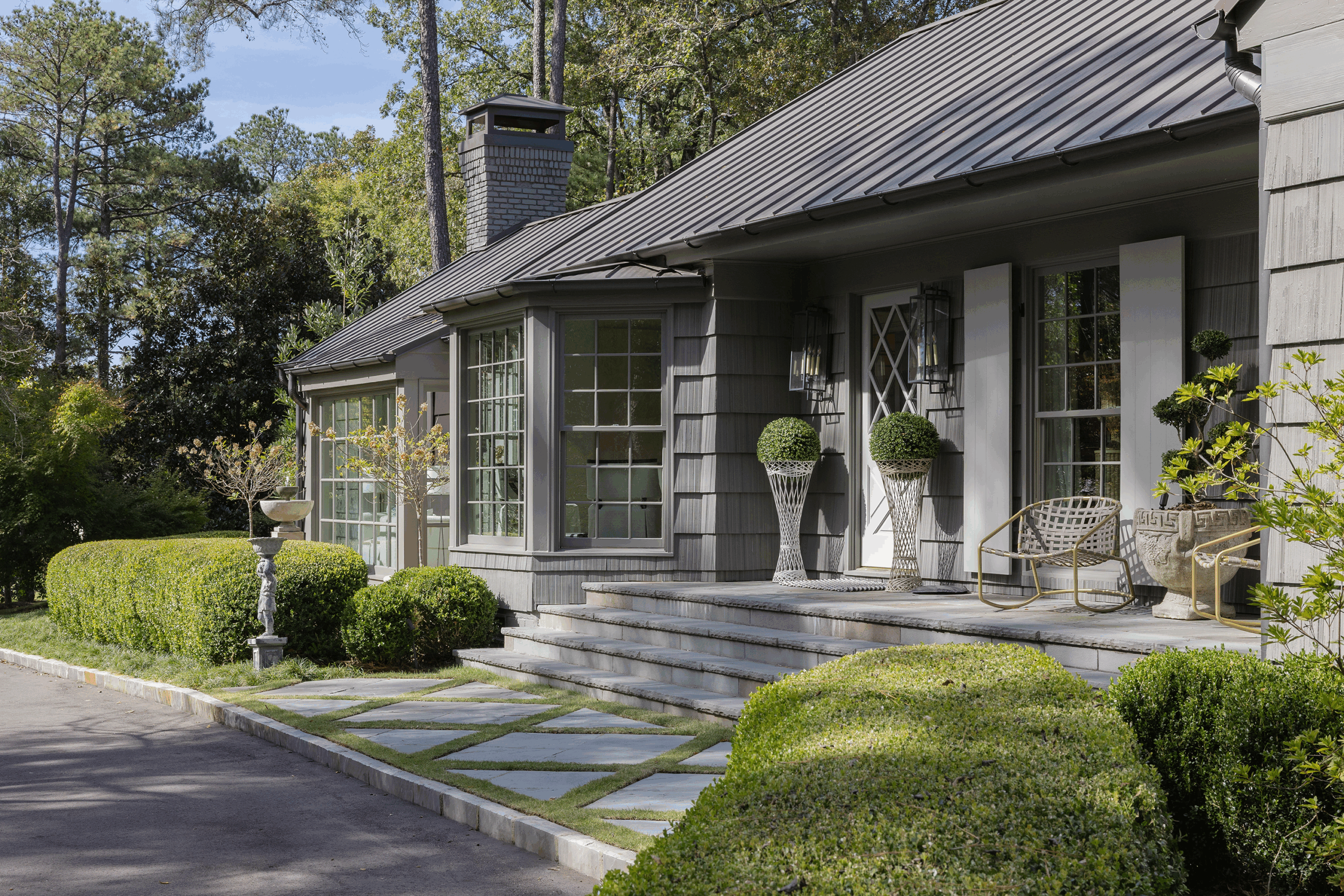 Gray-shingled 1950s cedar shake home with clipped topiaries and stone entry steps in Mountain Brook, Alabama