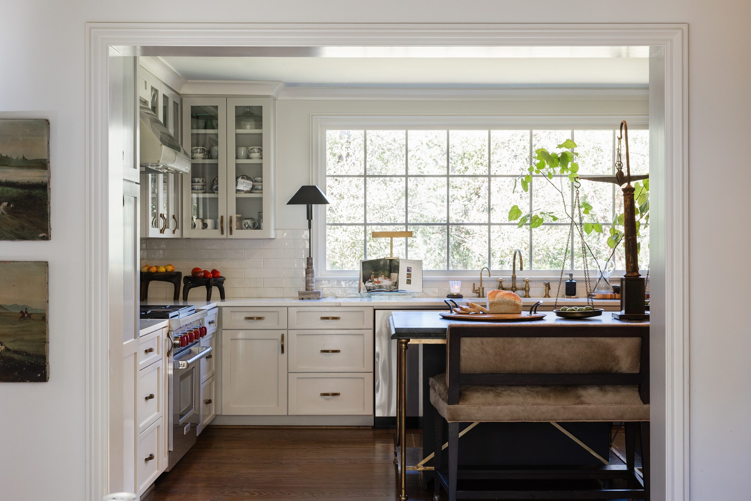 Cream kitchen with a brass-framed island, hide-upholstered counter stools, and French pie scales in a Mountain Brook home