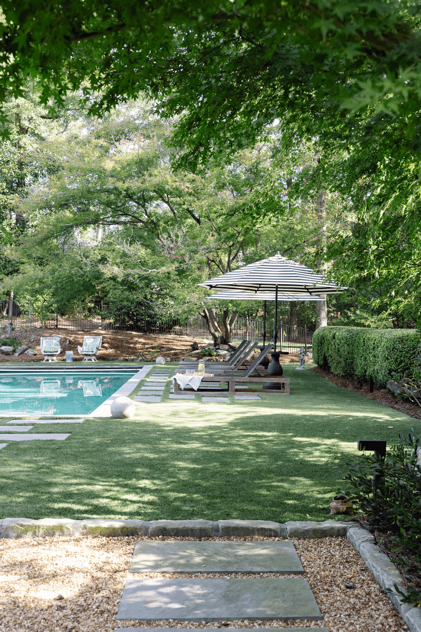 In-ground swimming pool and sun lounger deck surrounded by mature forest trees in a Mountain Brook backyard.